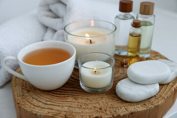 Spa composition with burning candles and cosmetic products on table, closeup