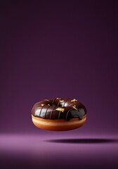 Delicious chocolate glazed donut with gold leaf decoration on a purple gradient background for sweet snack and dessert imagery