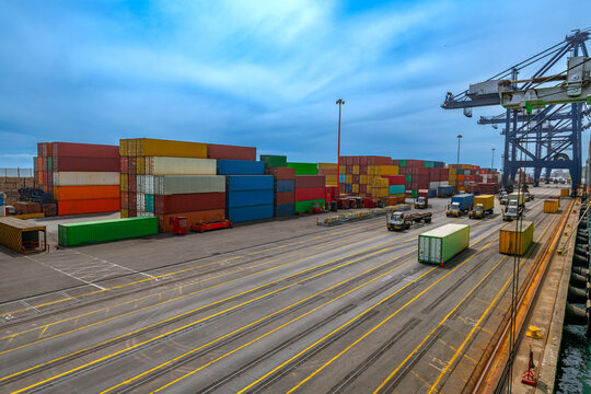 The bustling San Antonio Port, Chile, with containers of various colors neatly stacked and trucks moving along the docks.