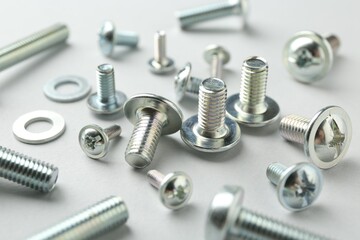 Many different metal bolts on light grey background, closeup. Hardware tool