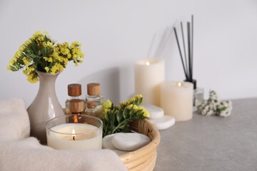 Spa composition with burning candles on light grey table, closeup