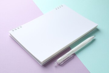 White notebook and pen on color background, closeup