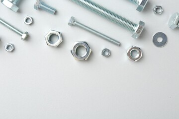 Metal bolts and nuts on white background, flat lay. Space for text