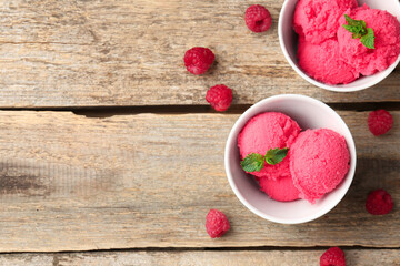 Delicious raspberry sorbet with mint in bowls and fresh berries on wooden table, flat lay. Space for text