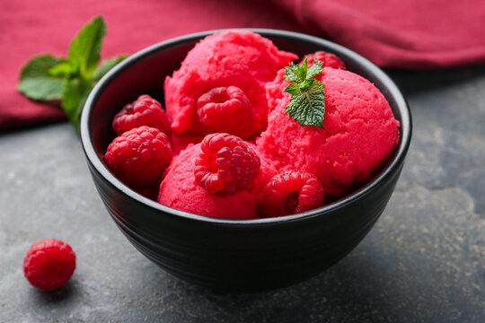 Delicious raspberry sorbet with fresh berries and mint in bowl on grey textured table, closeup