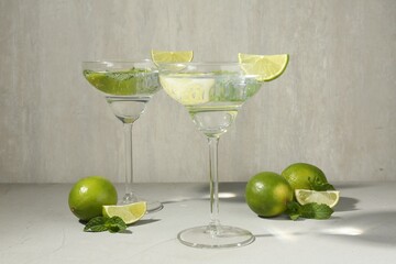 Martini cocktails with lime and mint on grey table