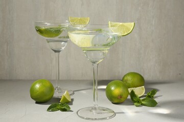 Martini cocktails with lime and mint on grey table, closeup
