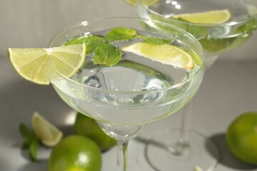 Martini cocktails with lime and mint on grey table, closeup