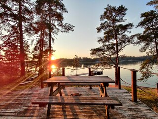 Terrace of a Finnish summer sauna house with chairs and table, overlooking pine forest and Baltic Sea archipelago. Peaceful retreat on island, traditional lifestyle and relaxation after sauna