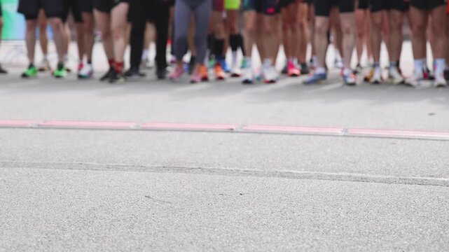 Marathon runners crowd, sportsmen participants start running the half-marathon in the city streets, crowd of sportswomen joggers in motion, group athletes outdoor training competition in summer day