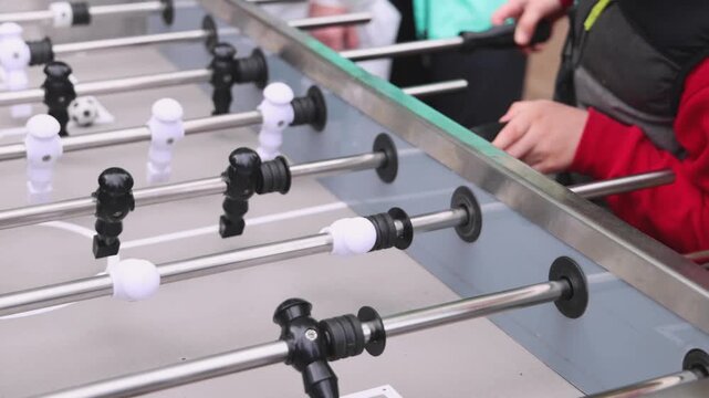 Group of friends playing kicker in a sports bar room, colleagues teammates play table football, table soccer game in the office, having fun, tabletop football match competition at work 