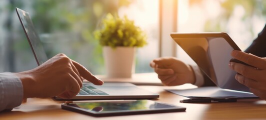 The collaborative workspace with laptops and tablets under warm sunlight.
