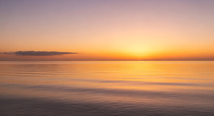 Obraz premium Golden hour sunset over the ocean water with a cloudscape and calm sea for background or wallpaper use