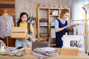 Asian dressmaker clothing partnership, fashion fabric small business packaging order delivery preparation, female partners managing clothing shop tasks together, balancing textile product shipment