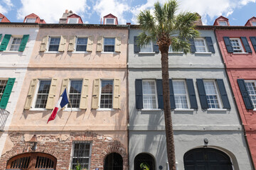Charleston, South Carolina, USA - July 2, 2025. Colorful historic building facades with shutters and a French flag in downtown Charleston.