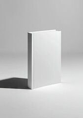 A stark white book stands upright on a minimalist white background, casting a subtle shadow, showcasing a clean, blank cover