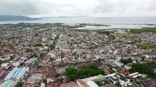 A stunning 4K aerial shot of Banda Aceh, Sumatra, Indonesia. The drone pulls back and gains altitude while tilting left, revealing the coastal city with ocean in the background.