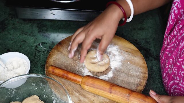 Dough close-up. Hands baking dough with rolling pin on wooden table. Young Indian woman hands hands keep rolling pin with flour on table, baking background.
