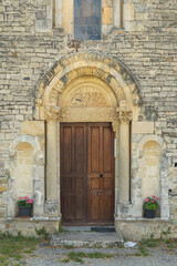 Romanesque Portal of Sainte Jalle Church in Drome, France, Showing Intricate Stone Carvings and Wooden Door