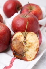Spoiled apple and good ones on white table, closeup
