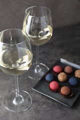Tasty wine in glasses and truffle bonbons on grey table, closeup