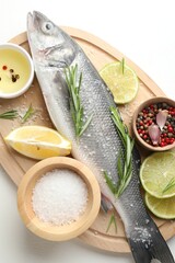Fresh raw seabass with spices on white table, top view. Fish and seafood delicacies