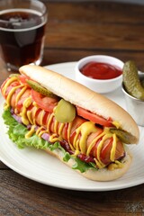 Tasty hot dog served with soda drink on wooden table, closeup