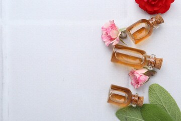 Bottles of cosmetic products, roses and sage on white table, flat lay. Space for text
