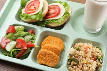 Plastic tray with tasty food and milk on table, closeup. School lunch