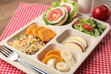 Plastic tray with tasty food, milk and fork on wooden table, closeup. School lunch