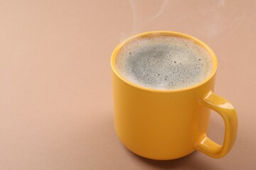 Aromatic coffee in cup on beige background, closeup. Space for text