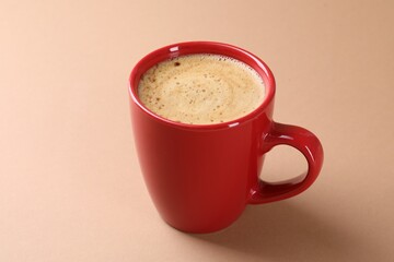 Aromatic coffee in cup on beige background, closeup