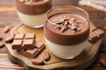 Delicious panna cotta with chocolate and cocoa beans on wooden table, closeup