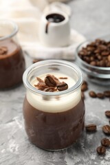 Delicious panna cotta with chocolate chunks and coffee beans on grey textured table, closeup