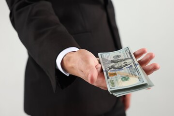 Man with dollar bills on light background, closeup
