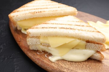 Tasty sandwiches with melted cheese on gray textured table, closeup