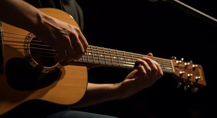 Person Playing Acoustic Guitar in Dim Lighting with Focused Hands and Warm Wood Tones