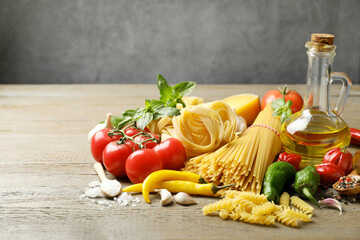 Different types of pasta and ingredients on wooden table, closeup. Space for text