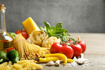 Different types of pasta and ingredients on wooden table, closeup