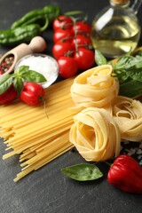 Different types of pasta and ingredients on black table, closeup