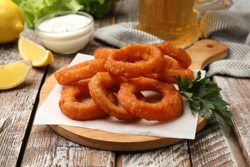 Fried squid rings served with sauce on wooden table, closeup
