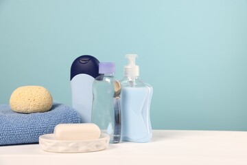Baby accessories and bathing products on white wooden table against light blue background, space for text