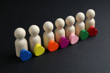 Tolerance concept. Human figures and colorful hearts on black background, closeup