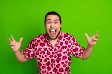 Fototapeta premium Expressive young man in a vibrant pink leopard print shirt gesturing enthusiastically against a bright green background