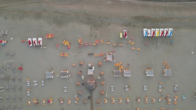 Beach Paradise: An overhead view captures a beachscape of umbrellas, chairs, and sunbathers lining the shore. A tranquil view capturing a sunny day and relaxed ambiance. 