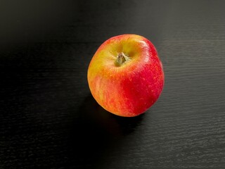 Fresh red apple resting on dark wooden surface
