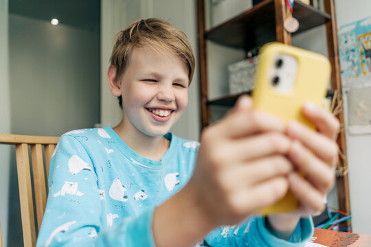 Laughing alpha generation boy uses a mobile phone.