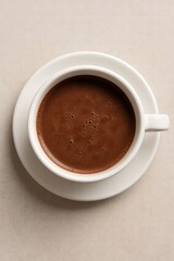 White cup filled with hot black coffee served on light background top view minimal style