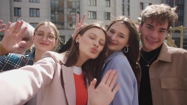 A group of happy people is sharing a fun moment. Young friends take a selfie picture during a leisure event. The team is traveling together. Smiling community portrait looking at camera