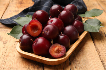 Whole and cut cherry plums on wooden table, closeup